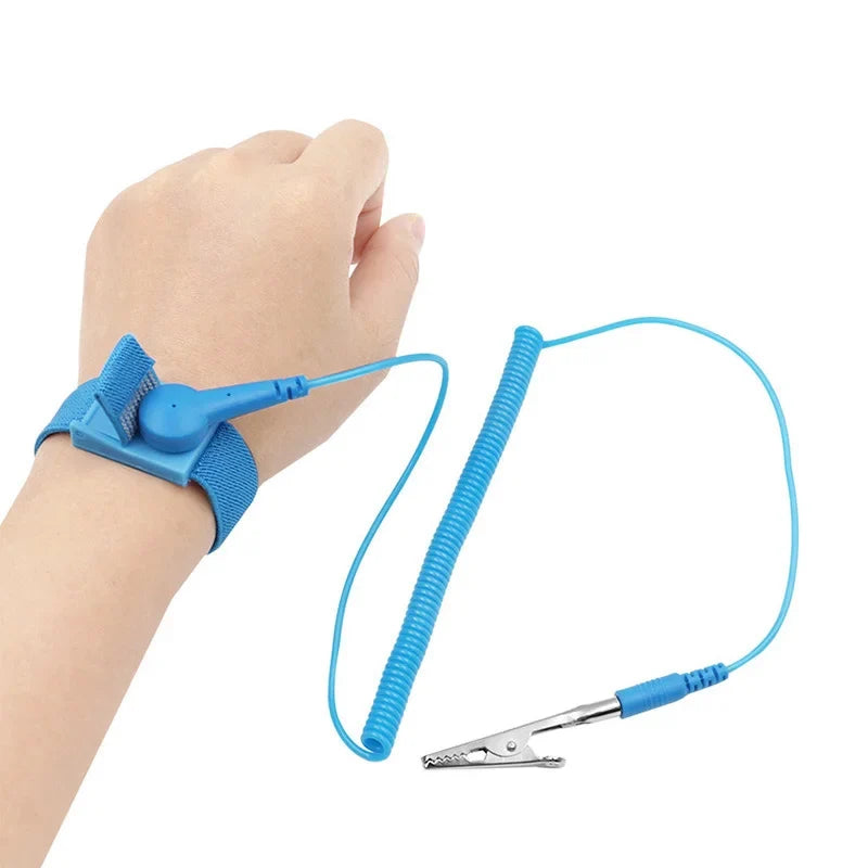 A hand is wearing a blue ESD wrist strap connected by a wire to a small metal clip.
