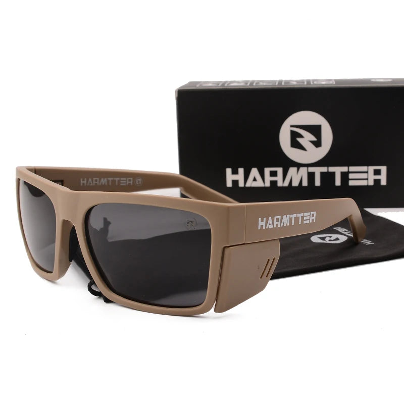 A pair of brown Armttee sunglasses resting on a black surface with the Harmttea logo box in the background.