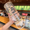 A hand holds a large capacity sport straw water bottle with a visible time scale, demonstrating its measurement features.