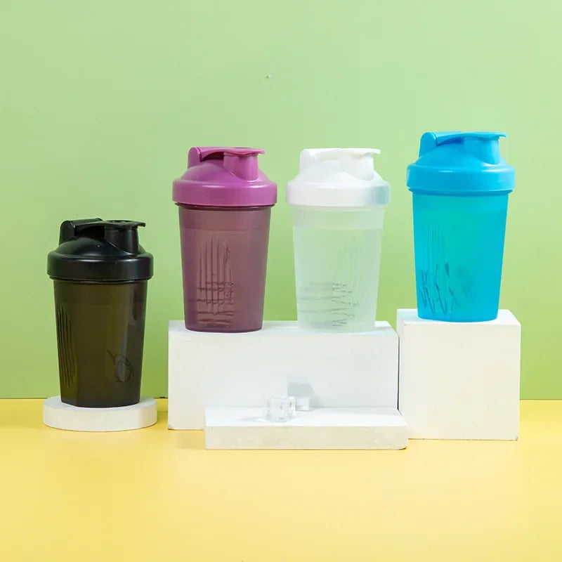 A set of four leakproof protein shaker bottles in purple, white, and blue are displayed on a light green background.