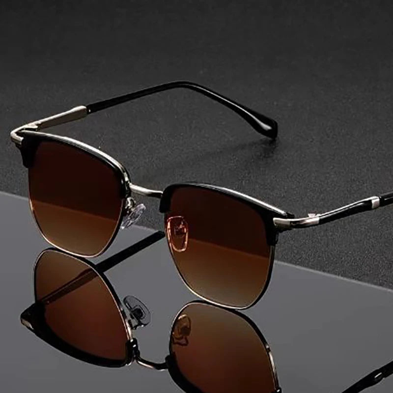 A pair of classic square metal frame sunglasses with brown lenses resting on a reflective surface.