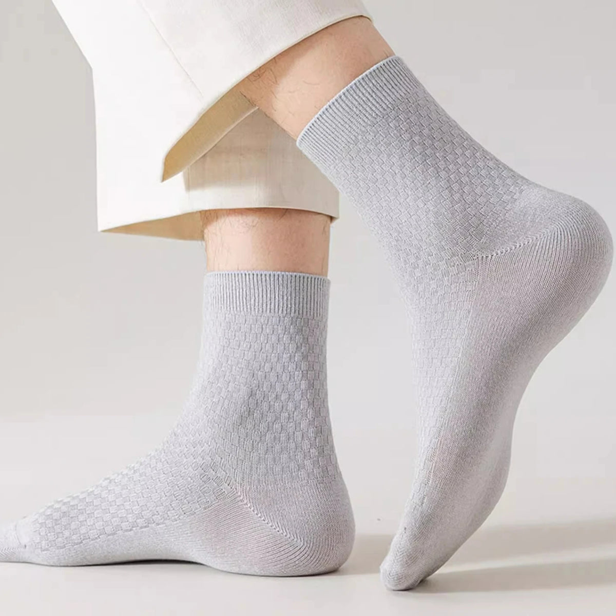 A close-up of light grey bamboo fibre anti-odor socks worn on a person's foot and leg.
