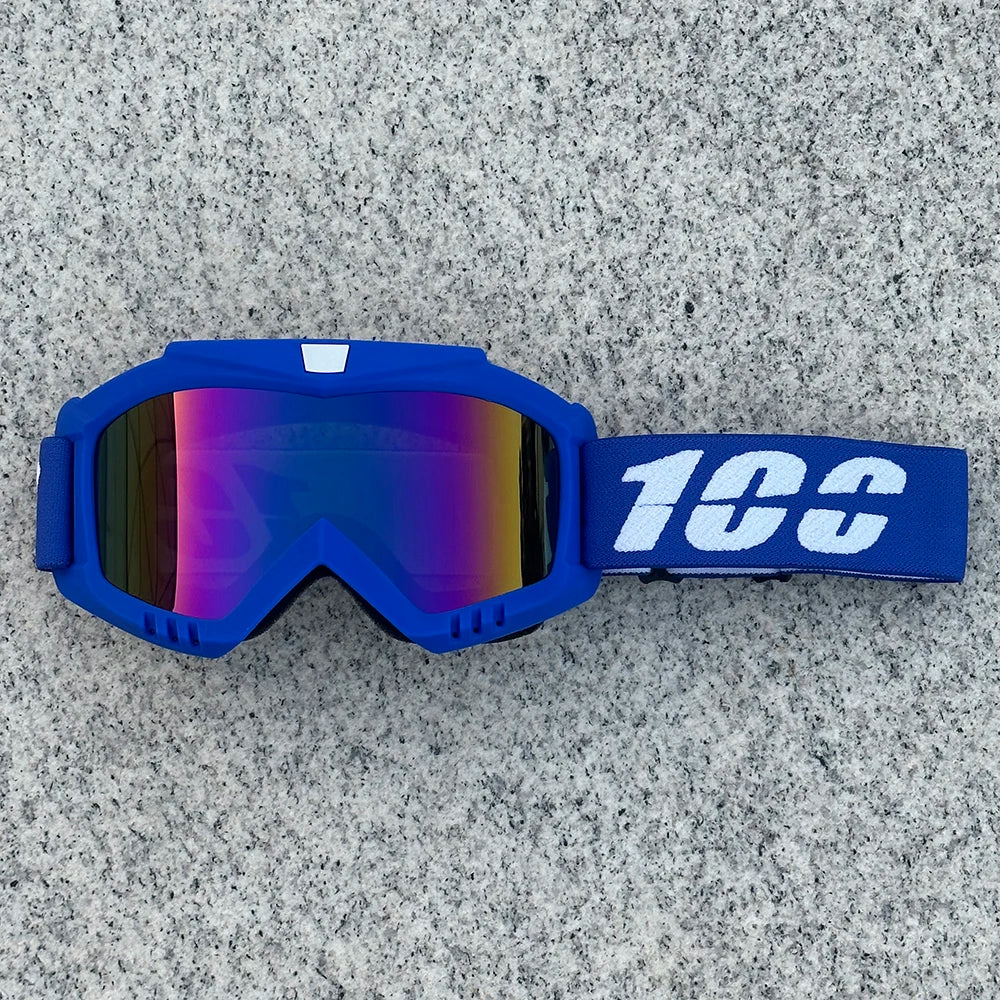 A pair of blue protective goggles with a white logo strap resting on a gray textured surface.