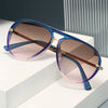 A pair of retro pilot sunglasses with gradient purple and pink lenses resting on a white surface.