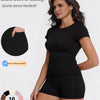 A woman models a black sports casual tracksuit consisting of a fitted top and shorts.