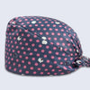 A navy blue cotton surgical cap with a pink polka dot pattern and white embroidered details.
