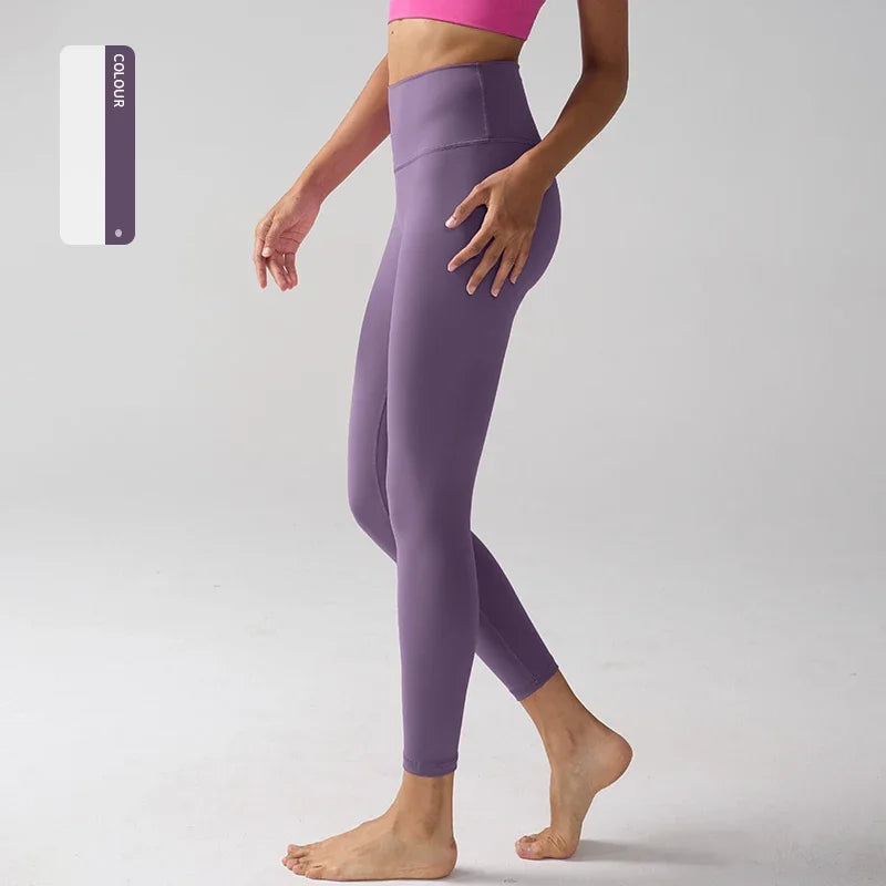 Un mannequin porte des leggings de sport violets taille haute et un haut rose, en position debout et posant.