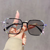 A hand holds a pair of black photochromic eyeglasses decorated with sparkling diamonds and rhinestones.