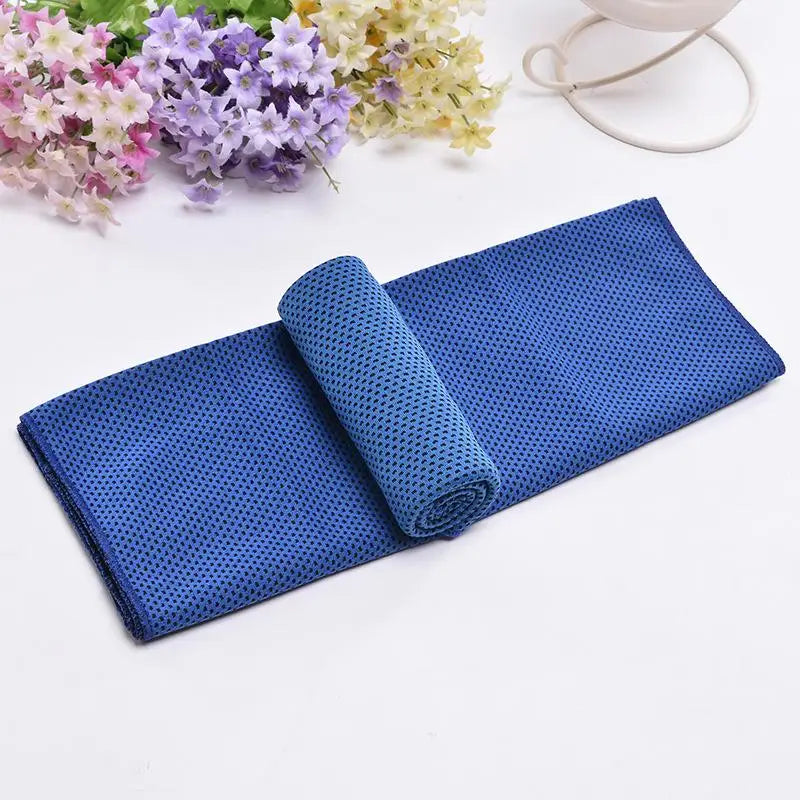 Serviette de refroidissement bleue et roulée à côté de fleurs violettes et jaunes.