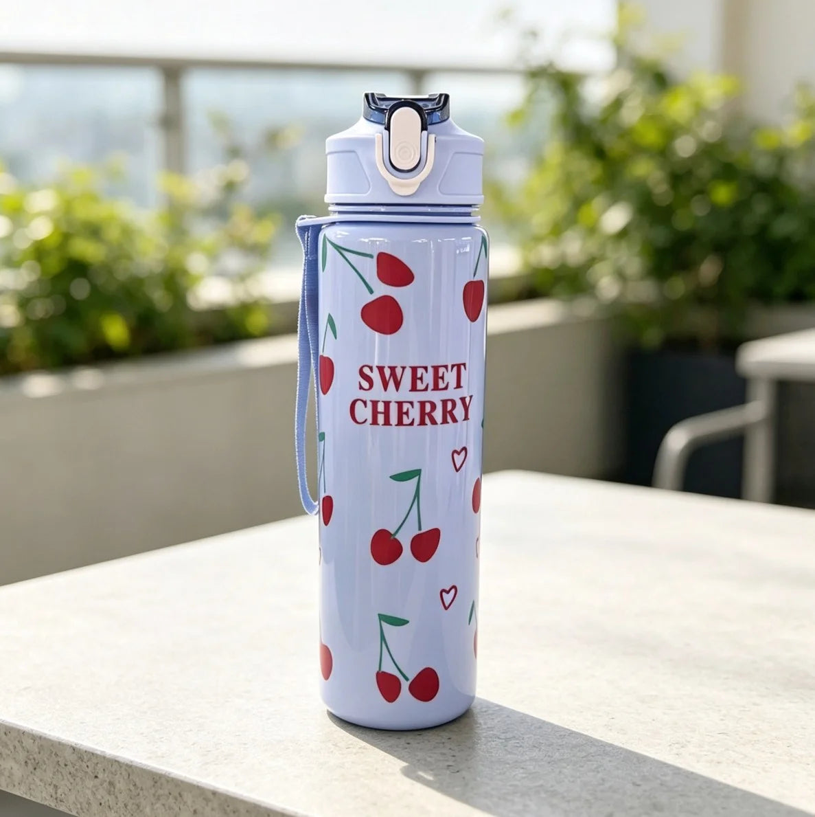 A light blue reusable water bottle decorated with red cherries and a strawberry design, sitting on a white surface.
