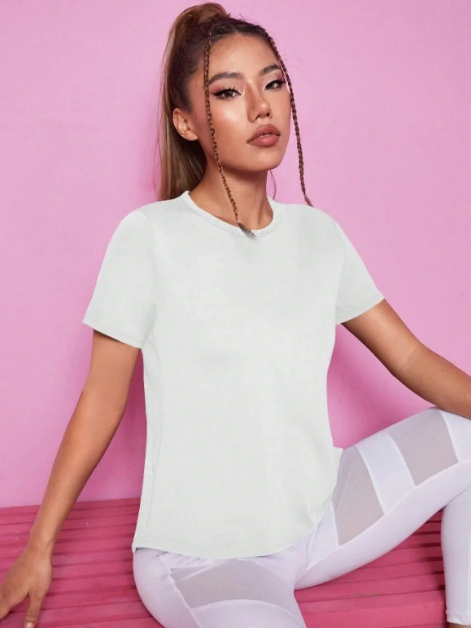 A woman models a white breathable summer yoga and fitness t-shirt in a studio setting.