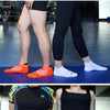 A variety of athletic ankle socks in various colors including gray, orange, black, and blue are displayed on a person's legs.