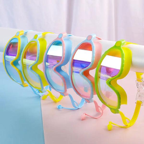 Una fila de gafas de natación coloridas para niños con grandes marcos, exhibidas en una superficie blanca.