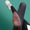 Gros plan d'une femme portant des leggings en peau de requin noire d'été et des chaussures de type slip-on de couleur claire.