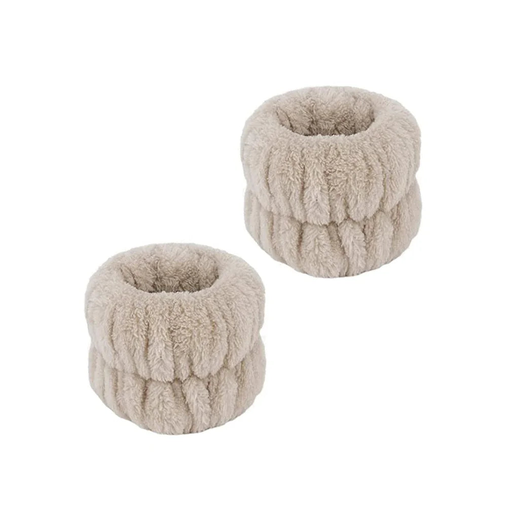 A pair of light beige microfiber spa headband and wristband set with a fluffy texture.