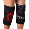 Manchettes noires pour genoux avec des motifs tribaux rouges portées sur la jambe d'une personne.