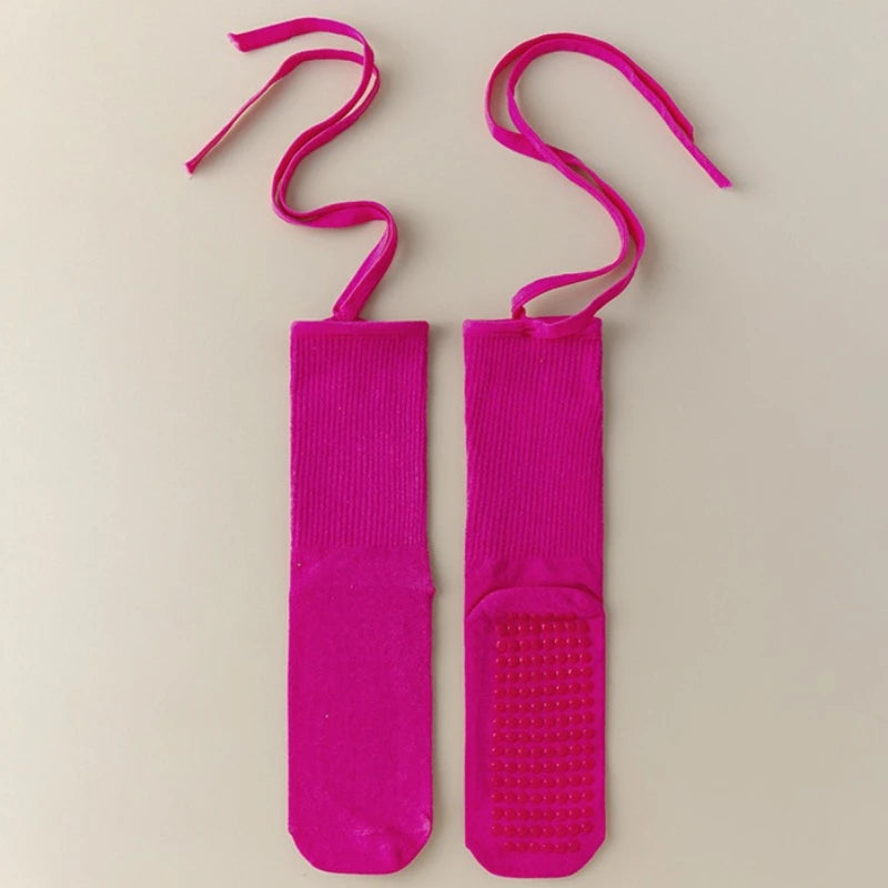 A pair of bright pink silicone anti-slip yoga socks with elastic drawstrings.