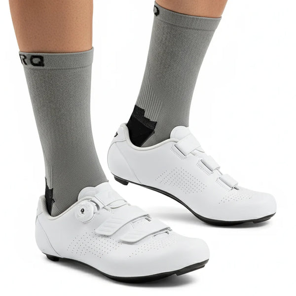 A pair of white cycling shoes and gray socks are shown on a person's foot.