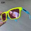 Ein Paar neongelbe Sonnenbrille mit blauen Rahmen wird in einer Hand vor einem hellgrauen Hintergrund gehalten.