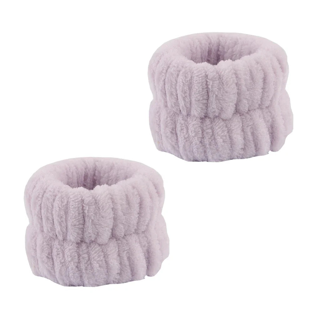 A pair of light purple microfiber spa headband and wristband set with a fluffy texture.