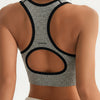 A gray seamless racerback sports bra top with black trim and a matching white bottom visible from the back.
