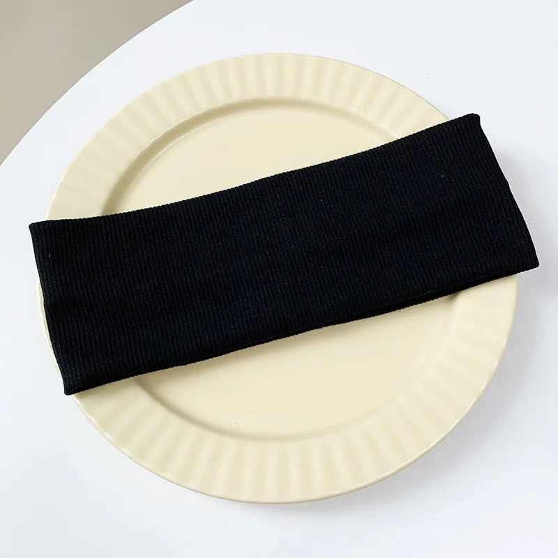 A black elastic hairband is placed diagonally across a light beige plate.