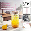 A glass tumbler filled with yellow liquid and a pink straw, displayed next to orange slices.