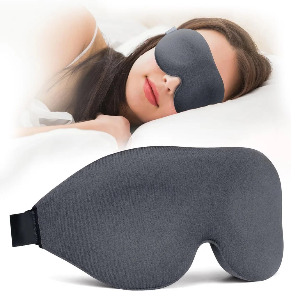 A gray light blocking sleep mask is shown being worn by a woman resting on a pillow.