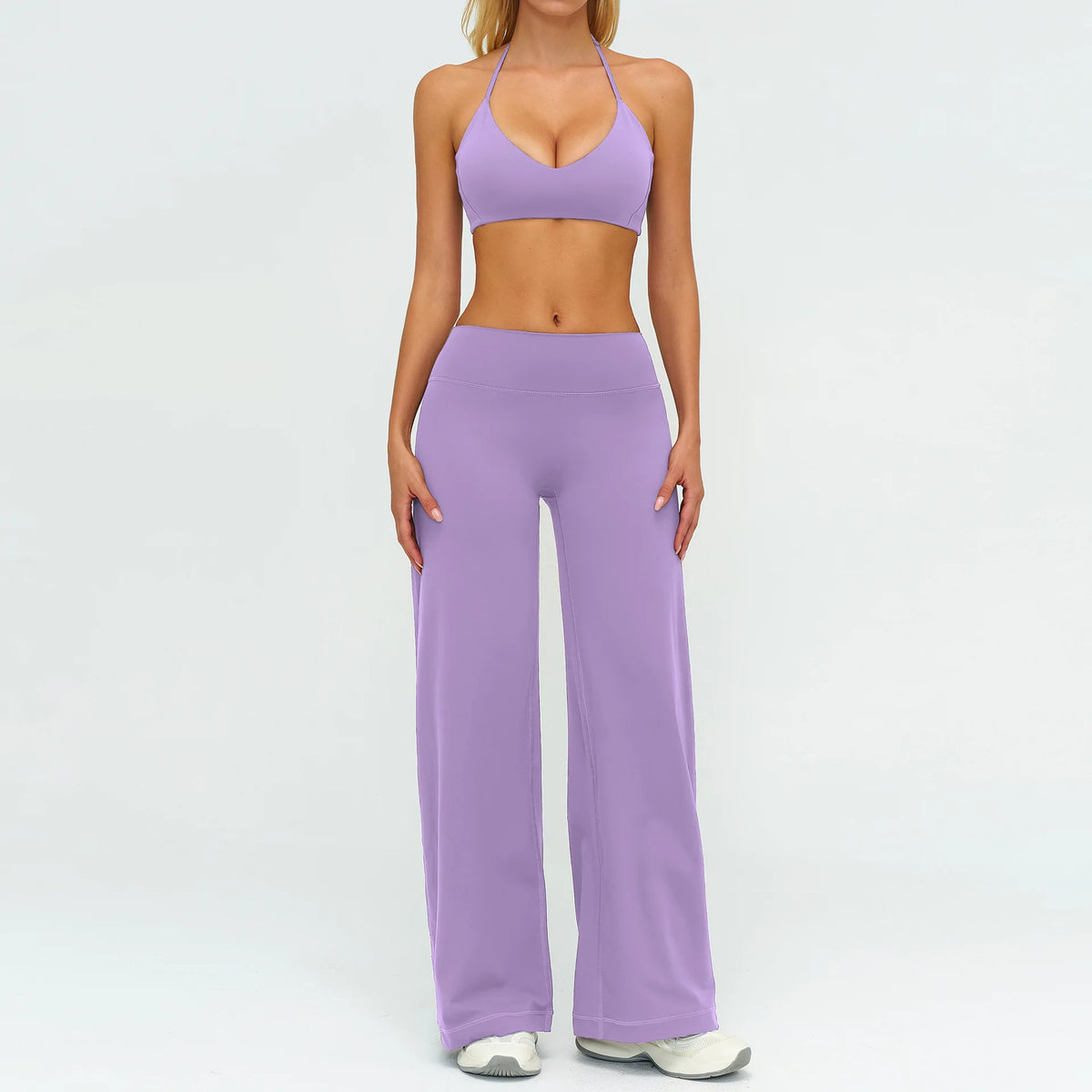 A woman wearing a purple women's premium fitness tracksuit consisting of a sports bra top and matching long pants.