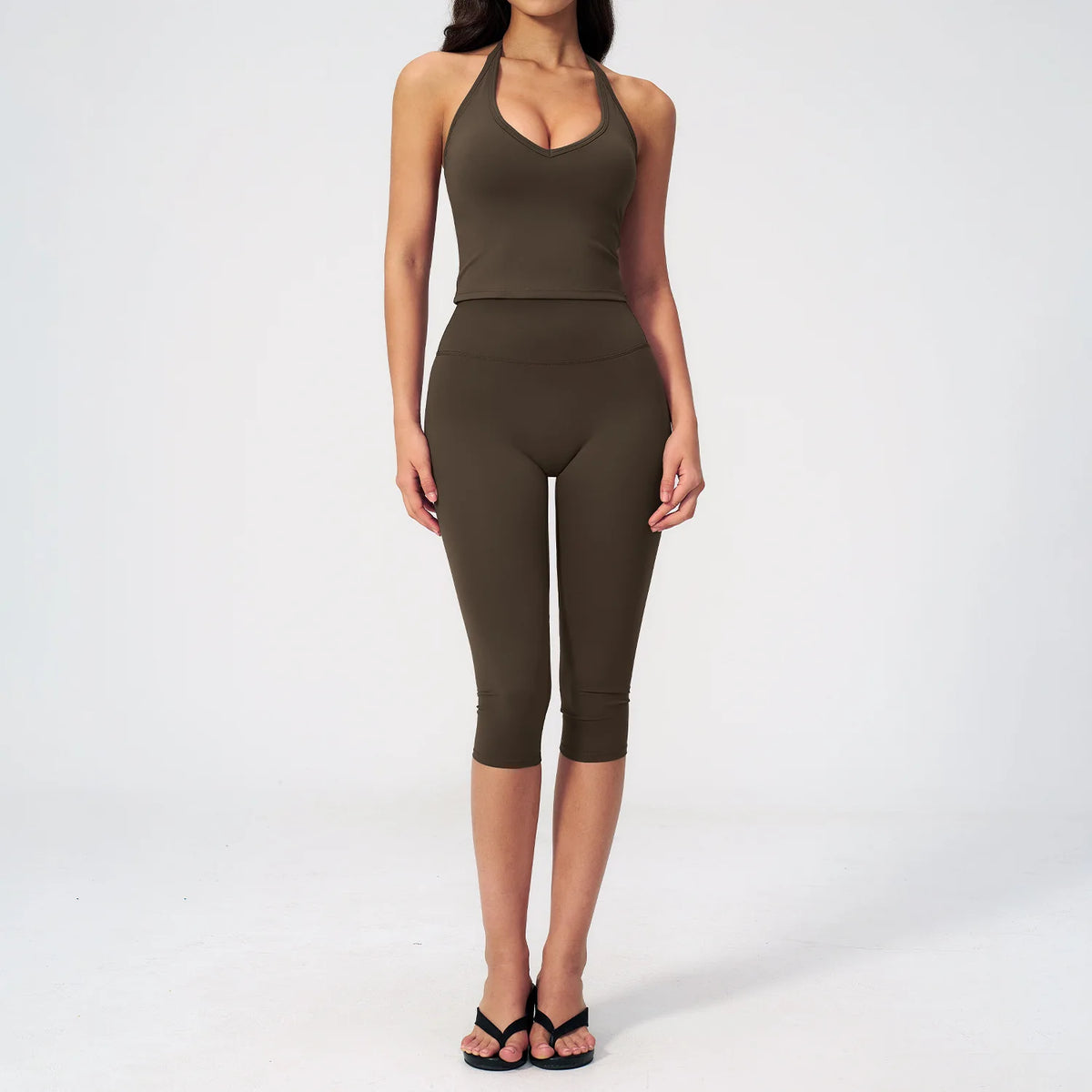 A woman wearing a dark olive green women's premium fitness tracksuit top and leggings.
