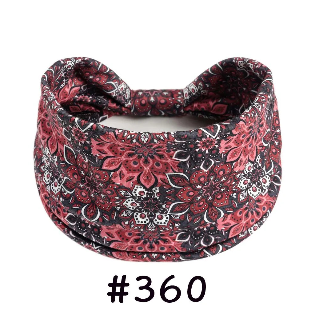 A close-up of a patterned, knotted cotton headband with a floral print in shades of pink and black.