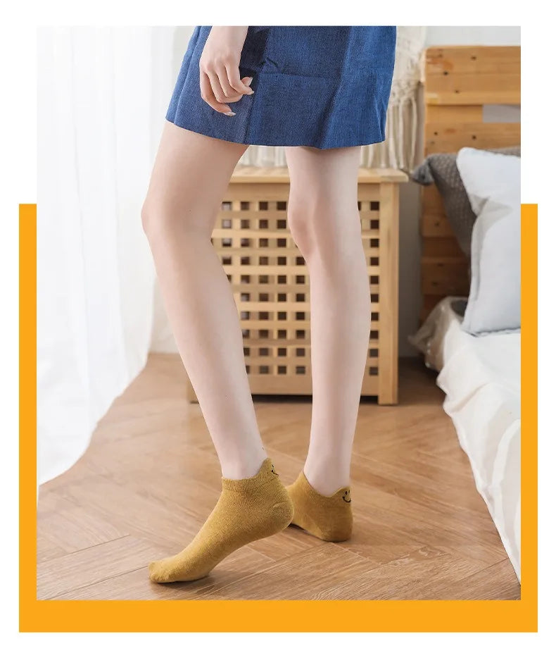 Una mujer viste un blazer azul y pantalones grises claros, mostrando calcetines amarillos para los tobillos.