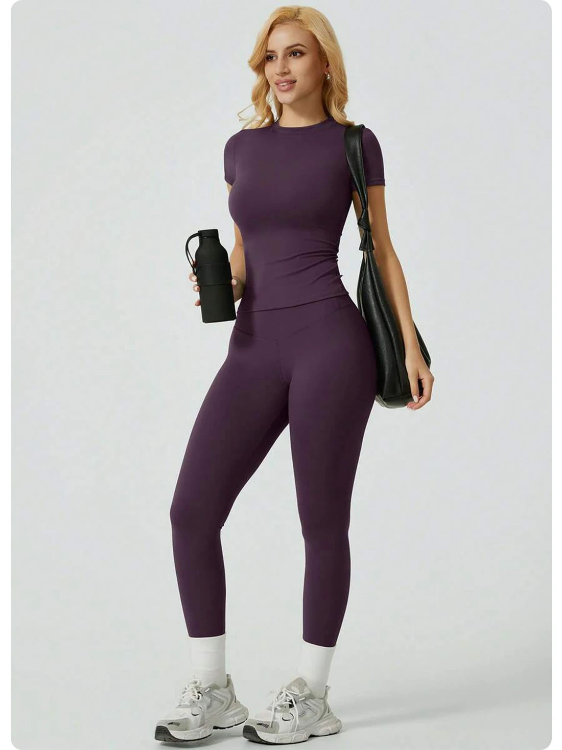 Eine Frau modelliert ein lila Zweiteil-Yoga-Set mit hohen Leggings und einem kurzärmeligen Oberteil.