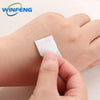 Une main applique un petit pansement adhésif waterproof blanc sur un doigt.