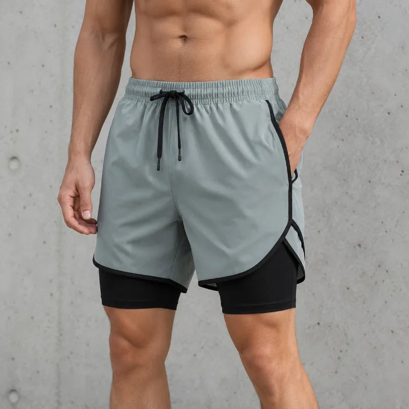 A man wearing gray quick-dry athletic shorts with black trim and a drawstring, standing against a concrete background.