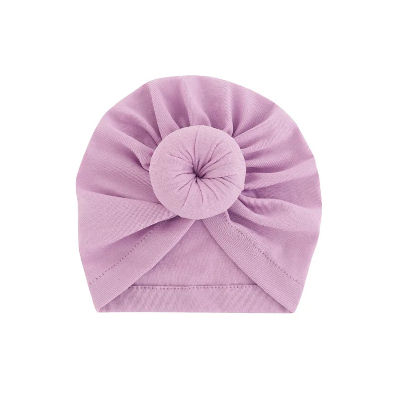 Ein fester lavendelfarbener Baumwollkindlicher Turban in Rosettenform gefaltet.