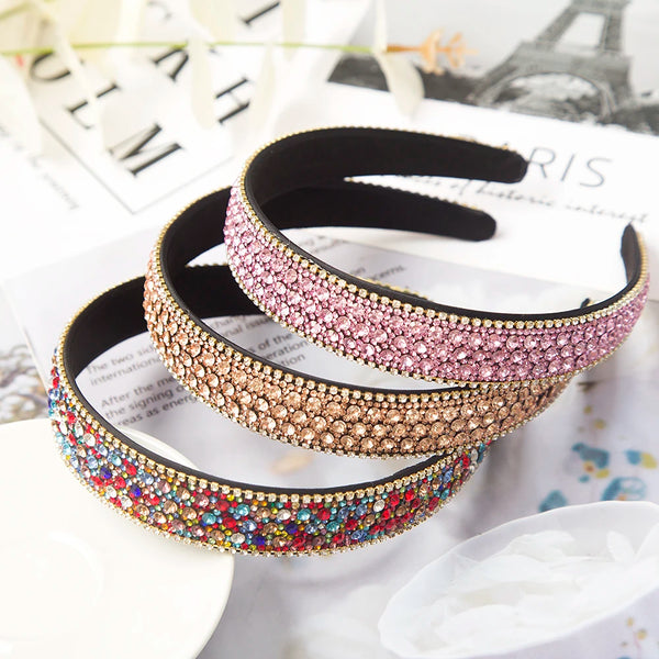 Un bandeau pour cheveux en strass de cristal rose et or, présenté sur une surface blanche.
