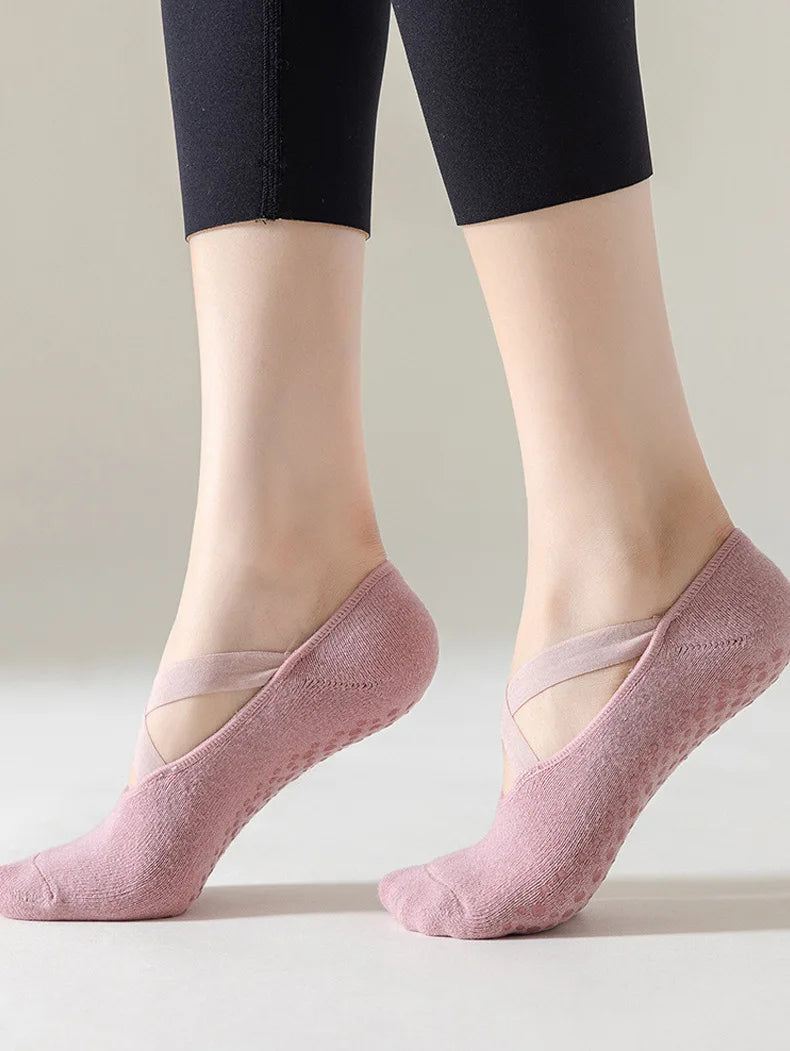 A pair of light pink non-slip yoga and gym socks with silicone grip worn on a person's feet.