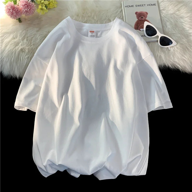Ein weißes, überdimensioniertes Baumwoll-T-Shirt für Damen wird neben einem Teddybär und Sonnenbrille präsentiert.