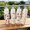 Four white tumblers with strawberry and cherry designs are lined up on a wooden table.