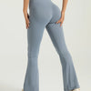 A model is wearing light blue high-waisted bootcut yoga pants while standing.