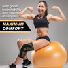 A woman demonstrates the comfort and sweat absorption of a black knee compression sleeve while sitting on an orange exercise 