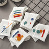 A stack of five white breathable cotton socks with colorful embroidery laid on a gray grid background.