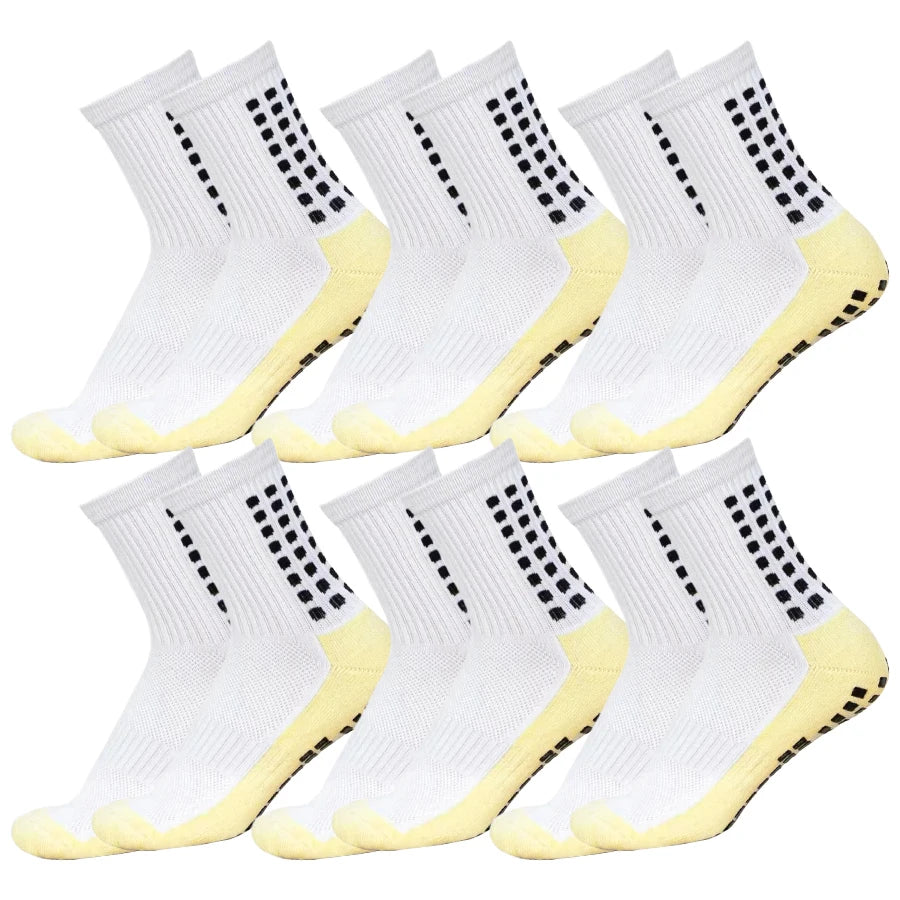 A set of white socks with black dots and yellow grip soles for sports.