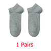 Un par de calcetines unisex de algodón transpirable y color gris claro, extendidos planos.