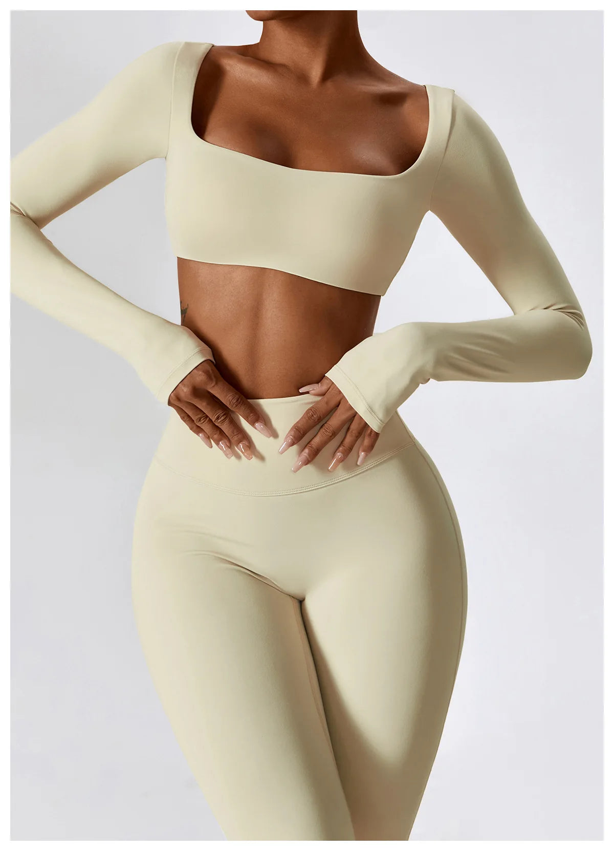 A model wearing a beige long-sleeved crop top and matching high-waisted leggings from a women's performance tracksuit set.