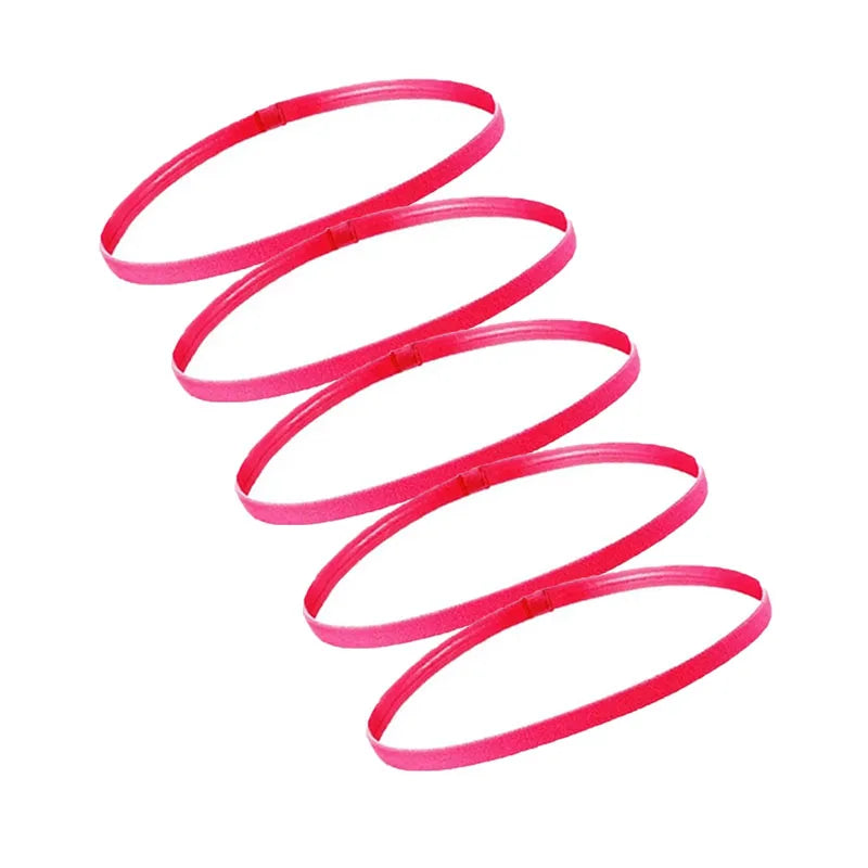 A set of five bright pink elastic sports headbands coiled in a spiral shape.