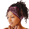 A woman with dark curly hair wears a maroon patterned fabric headband for yoga or workout.