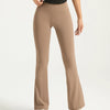 A model wearing high-waisted bootcut yoga pants in a beige color.