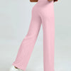 A woman wearing light pink high waisted yoga pants and white sneakers.
